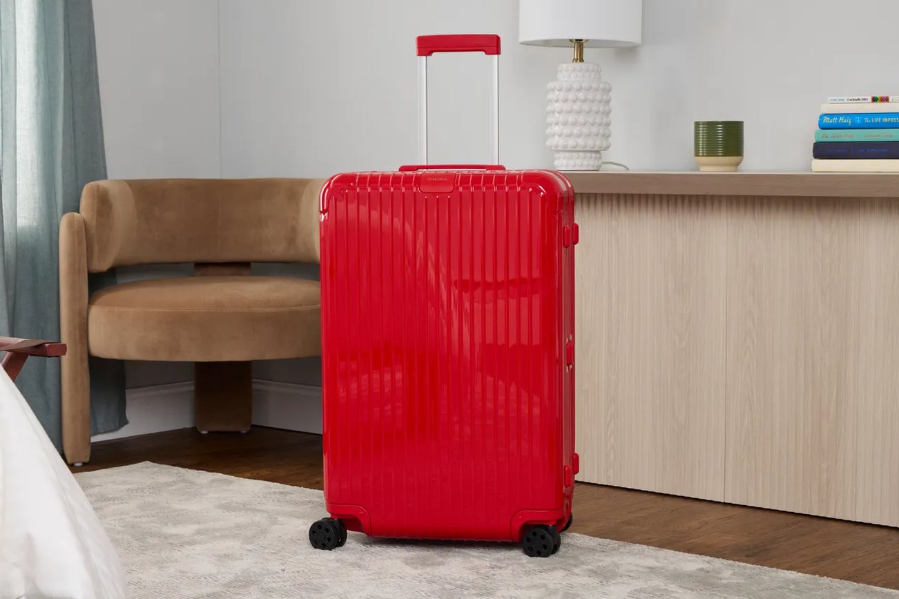 worn carry-on suitcase sitting at an airport gate, scuffed corners visible