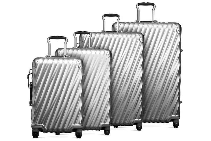 hard-shell carry-on open on a hotel bed, packed